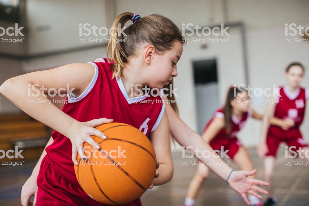 Skillful Teenage girls practicing defensive game at basketball training in school gym